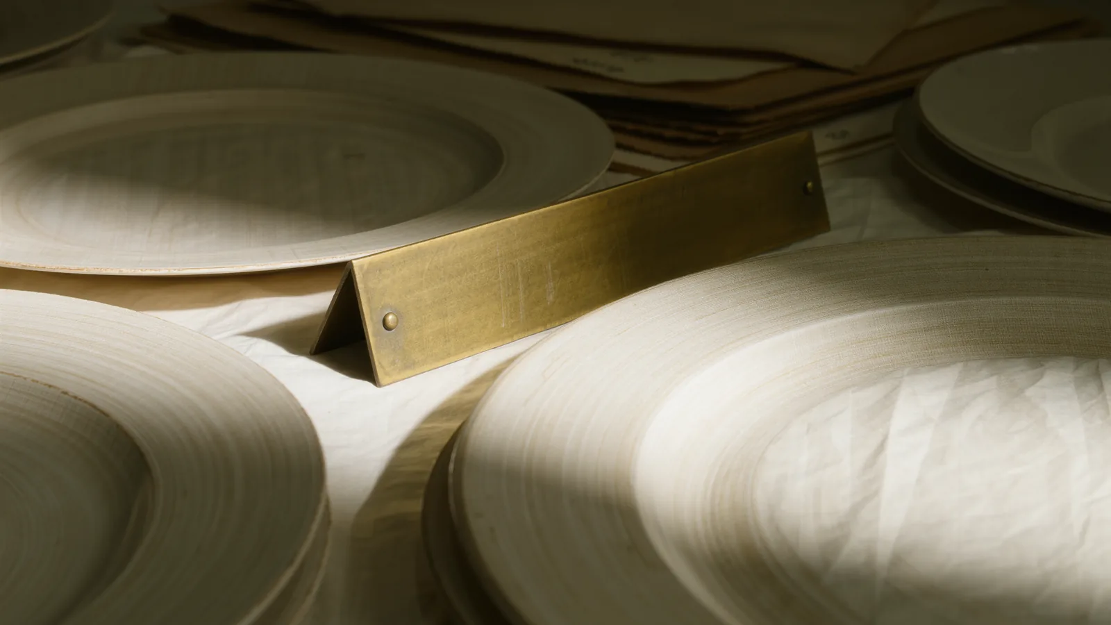 One engraved brass nameplate among blank ivory plates under a single spotlight