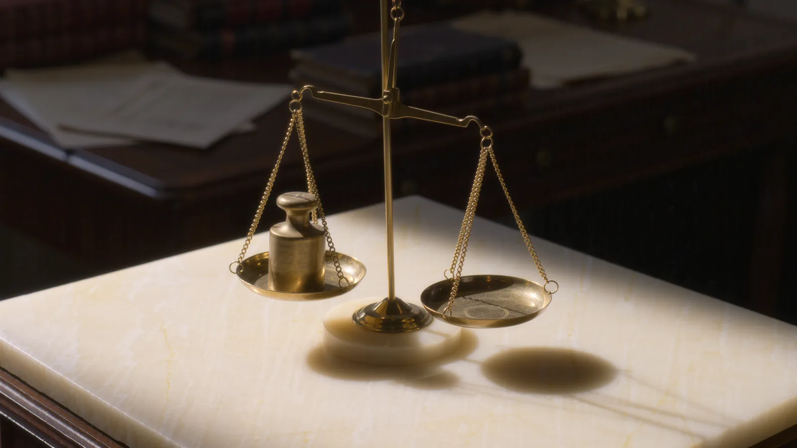 A single gold coin on a brass balance pan