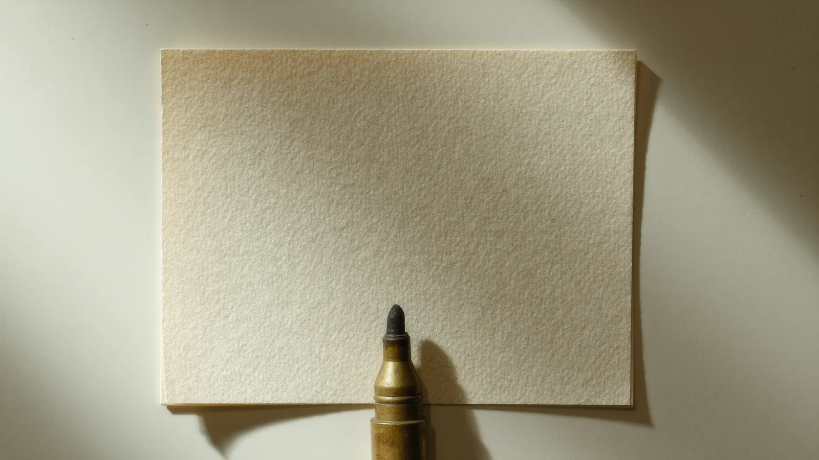 A pale sheet with a fountain pen and a small brass stamp